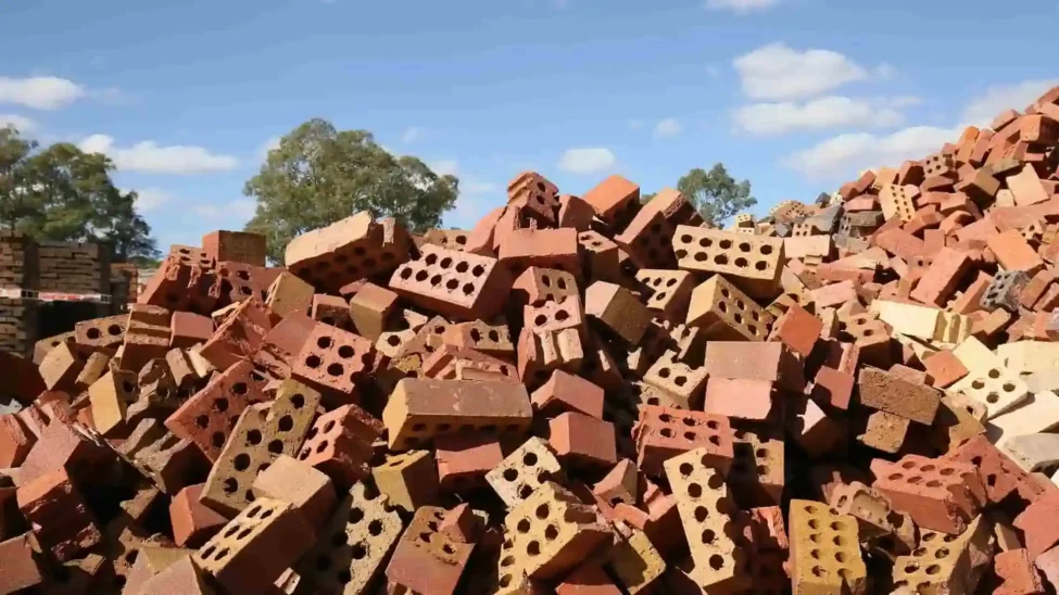 A pile of different types of bricks showcasing the best bricks for construction, stacked outdoors under a clear sky.