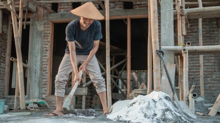 A construction worker mixing cement at a building site, showing the process of preparing the best cement for construction.