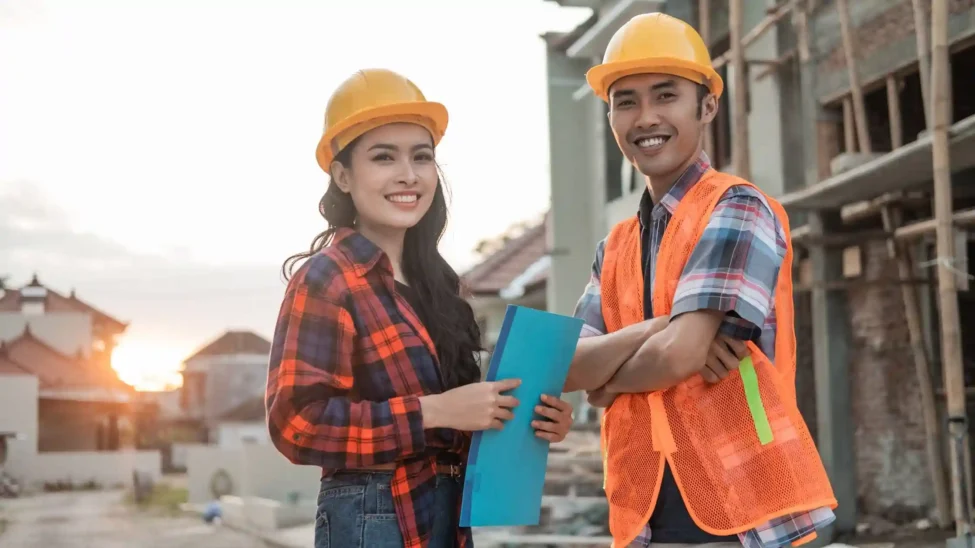 Two students wearing safety helmets and vests at a construction site, representing hands-on training from the best construction management schools.