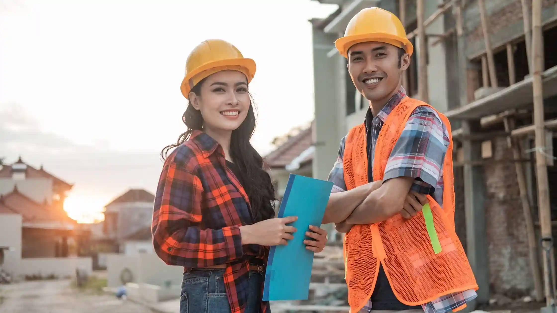 Two students wearing safety helmets and vests at a construction site, representing hands-on training from the best construction management schools.