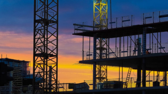 Steel framework and cranes at a construction site during sunset showcasing the best steel for construction.