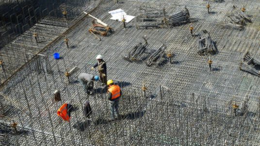 Construction workers reinforcing the foundation with steel bars, highlighting the importance of using the best steel for construction to ensure a strong and durable structure.