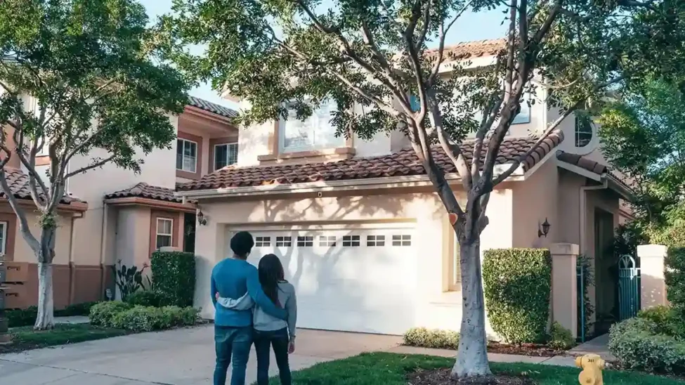 Couple looking at a house, symbolizing the dream of home ownership and the impact of home construction loan interest rates.