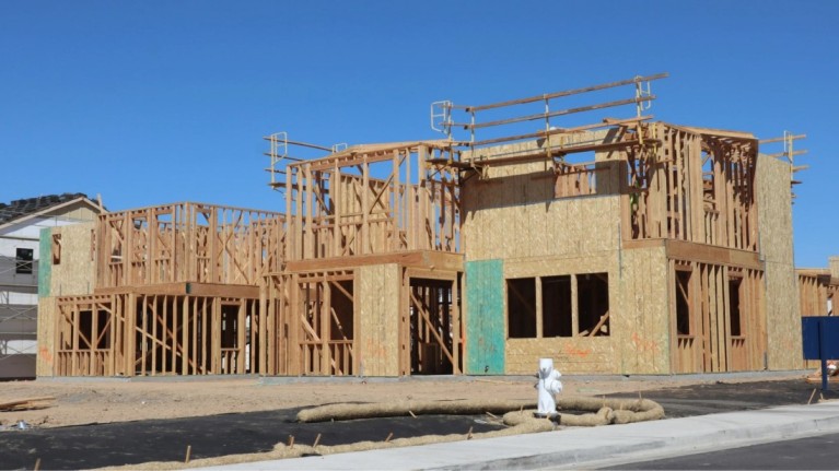 A house under construction, showcasing the wooden framework of its structure. the image captures the early stages of building, with beams and plywood panels forming walls and floors. It illustrates the process of framing in house construction as part of a step-by-step guide.