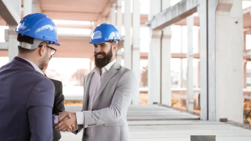 Handshake between two civil engineers after a project completed by various types of construction workers.