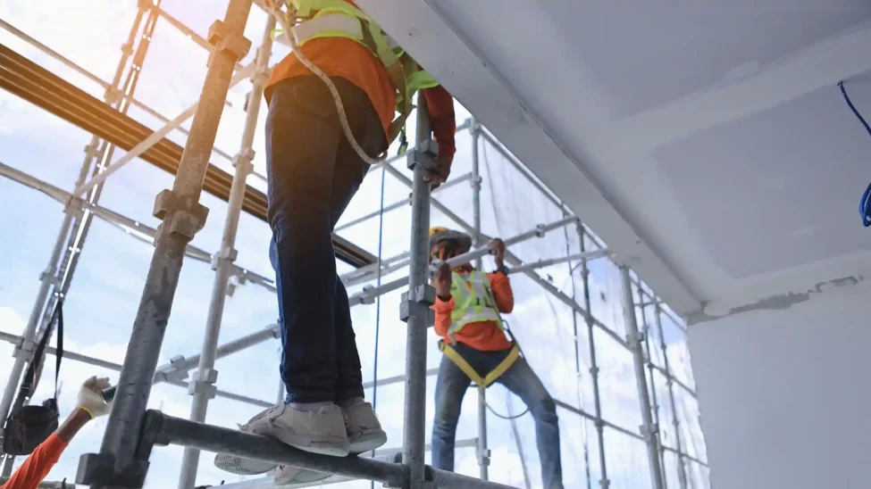 Workers assembling scaffolding on a construction site, showcasing various types of scaffolding in construction.