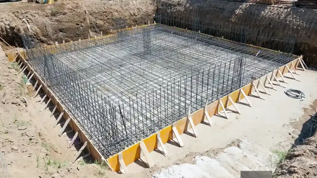 A reinforced steel framework prepared with types of sand used in construction at a building site.